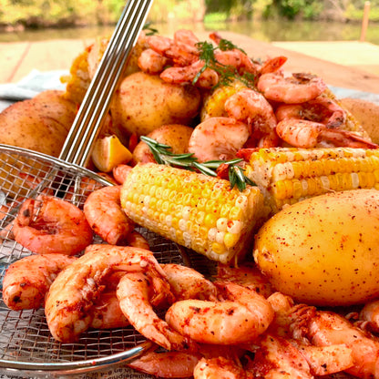 Boiled shrimp with corn and potatoes and a mesh skimmer outside
