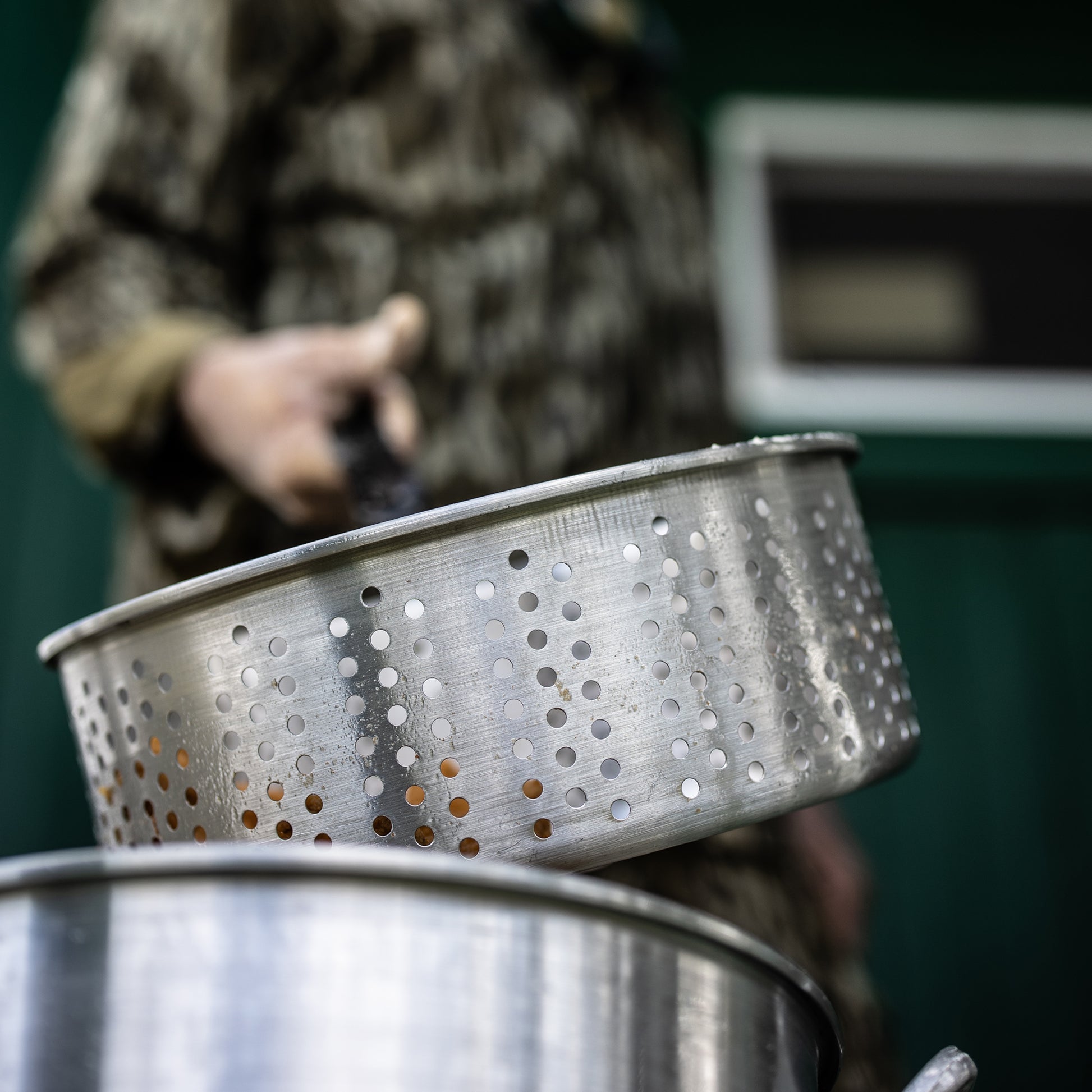 Aluminum fry basket held by a person with a blurred background