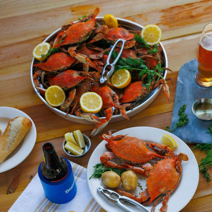 crabs in aluminum tray with lemons and a seafood cracker. Plate of crabs and other ingredients on a wood table.