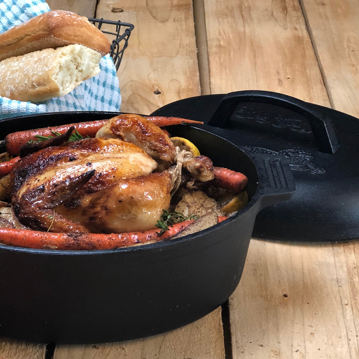 Cast Iron Oval Roaster with roasted chicken and carrots on a wooden surface