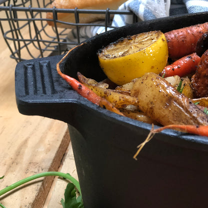 Close up of oval roaster with roasted chicken and vegetables on a wooden surface