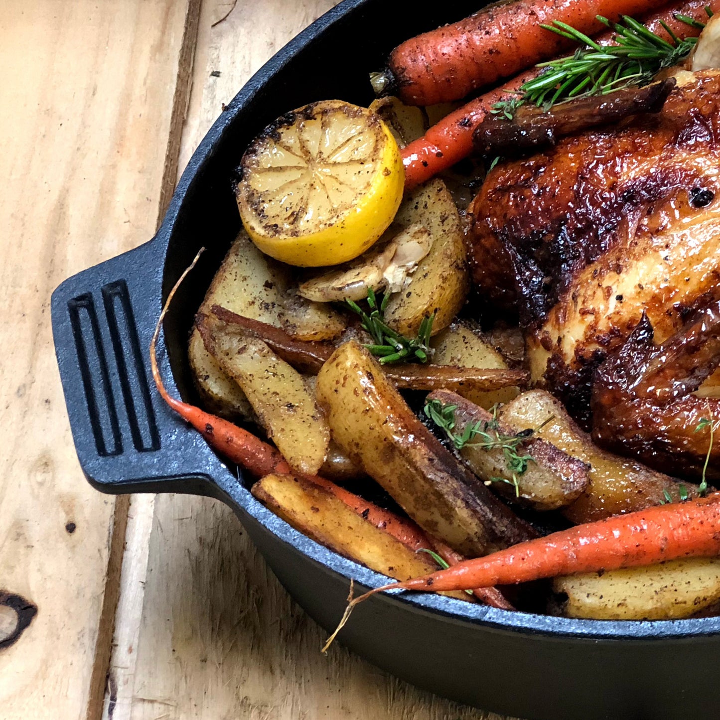 Overview with roasted chicken, potatoes, and carrots on a wooden surface