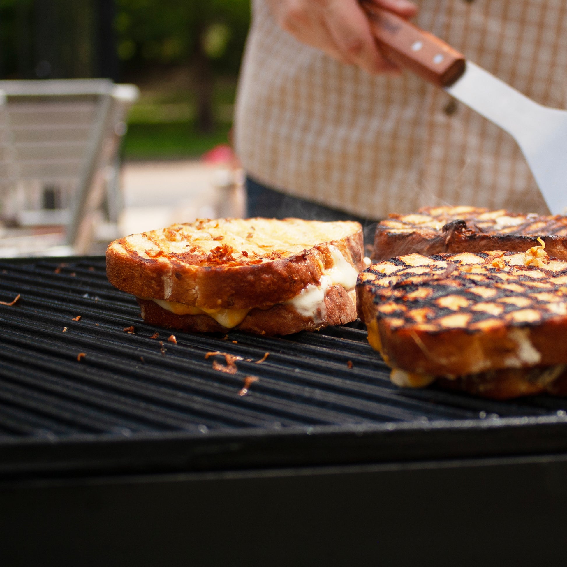 Grilled cheese sandwiches on a cast iron griddle being cooked outside