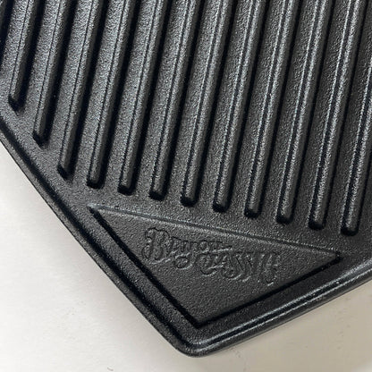 Close up of the ribbed side of a cast iron griddle on a white background.