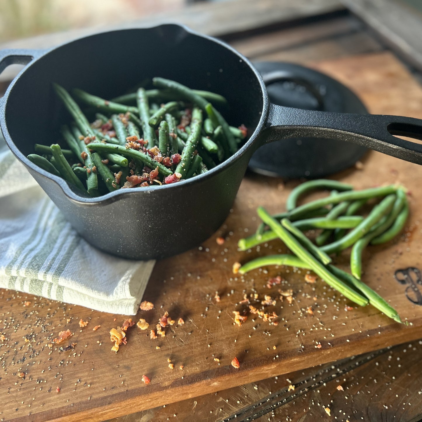 Black cast iron pot with green beans on a wooden surface