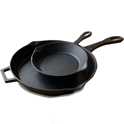 A set of two black cast iron skillets, one larger than the other, stacked inside each other on a white background.