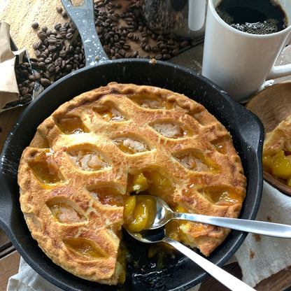 Cast Iron Skillet with partially eaten apple pie with spoons and coffee