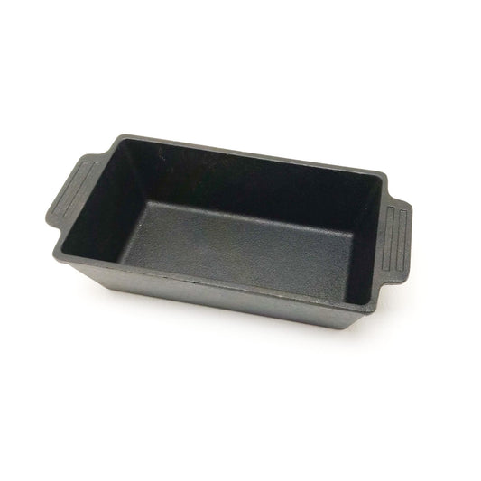 A black cast iron loaf pan with side handles, against a white background.