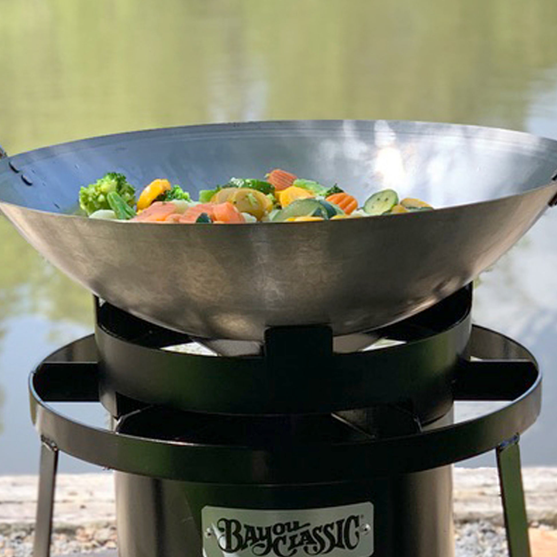 Steel wok with vegetables on an outdoor cooker
