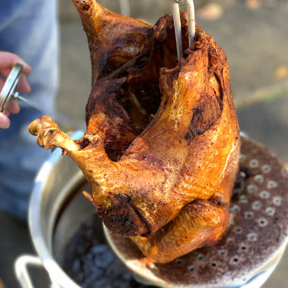 Fried turkey being pulled out of turkey fryer pot