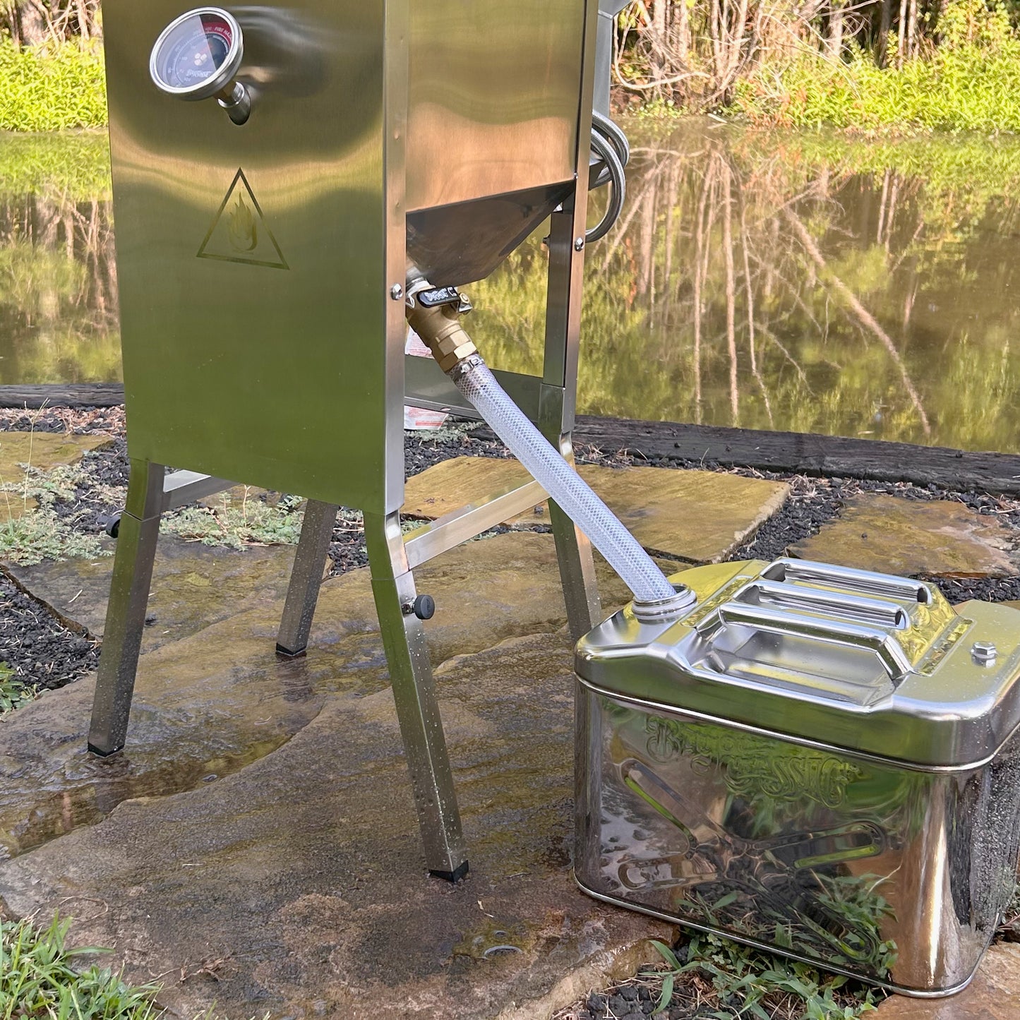 4-gal Bayou Fryer with jerry oil can and drain hose outdoors near a body of water