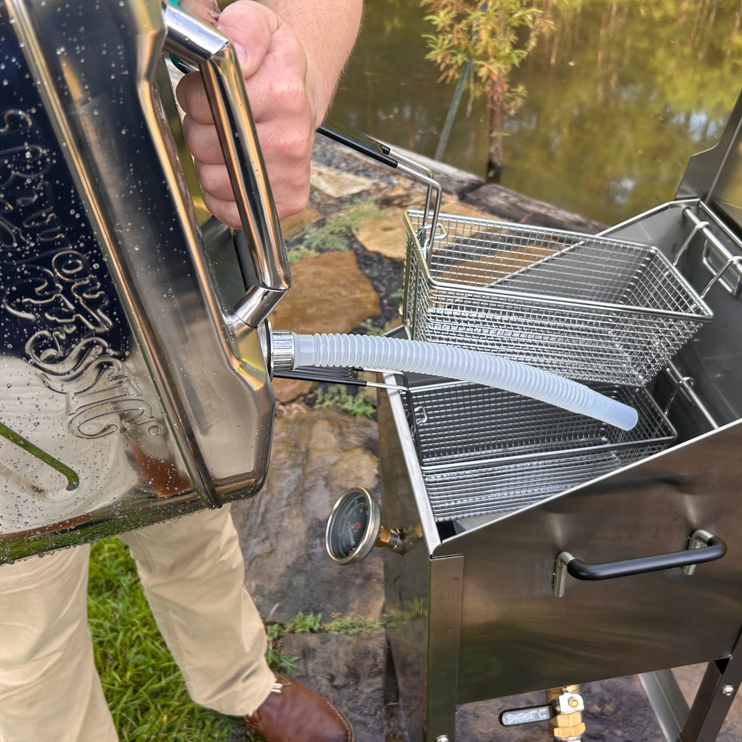 Person using a jerry oil can and a Bayou Fryer outdoors.