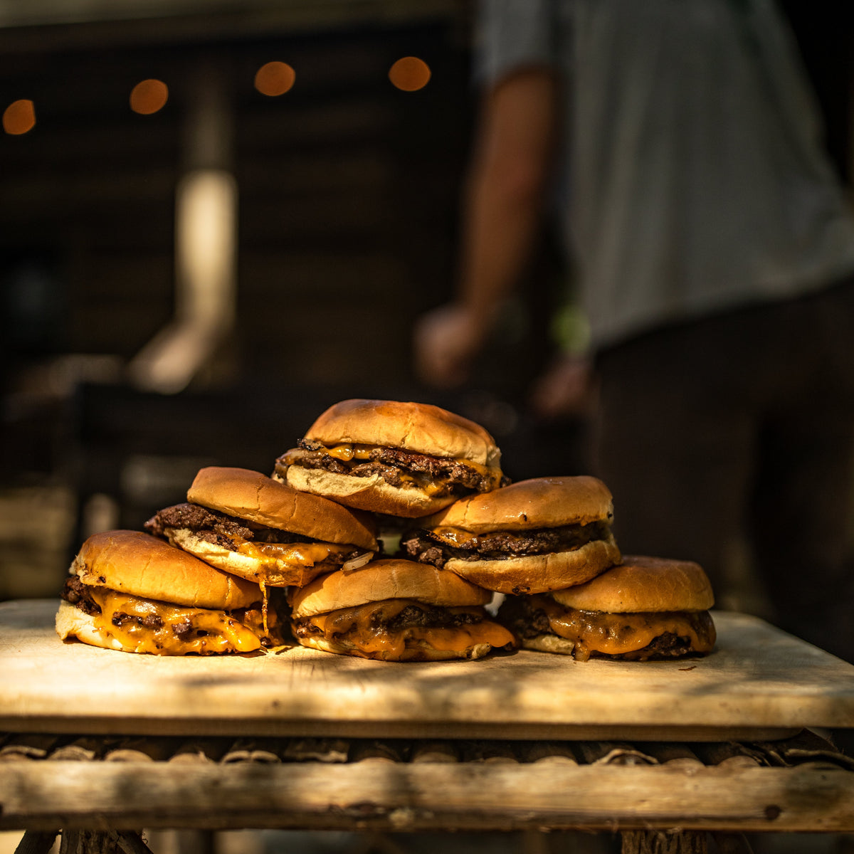 A stack of smashburgers with cheese in an outdoor setting