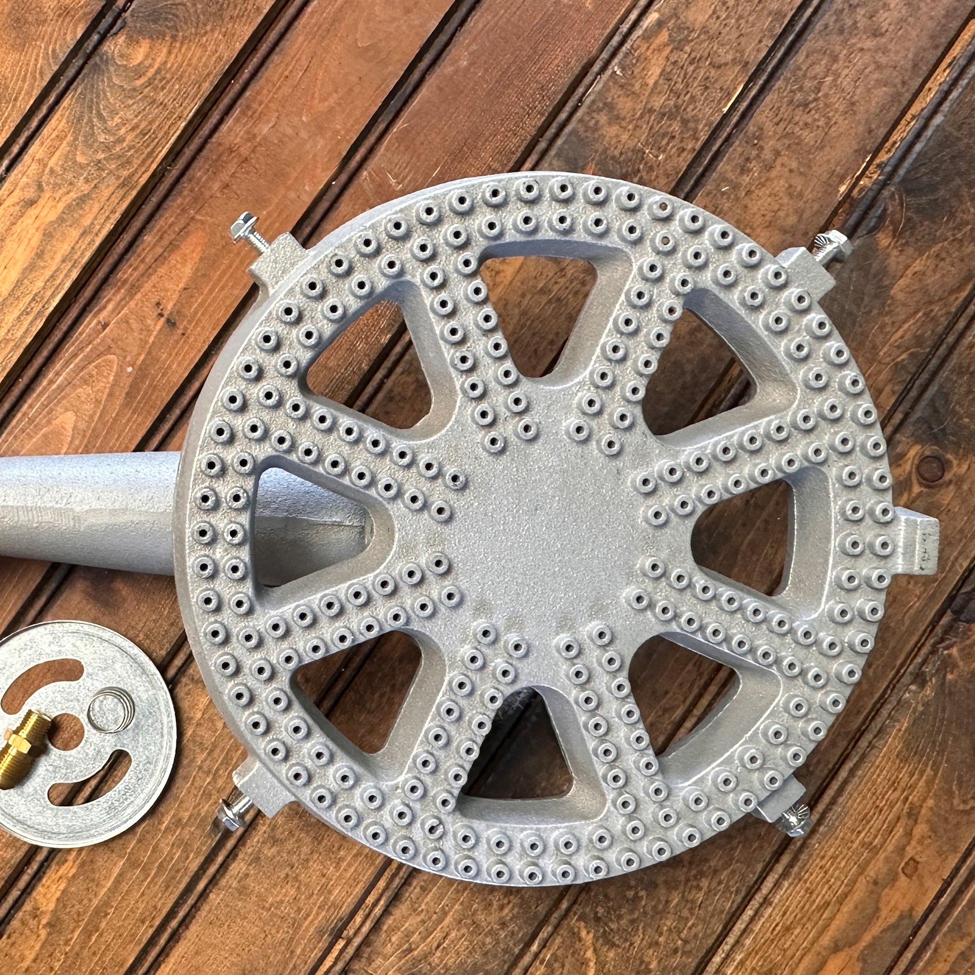 Cast iron banjo burner with orifice, air shutter, and spring on a wood surface.