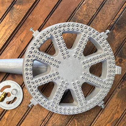 Cast iron banjo burner with orifice, air shutter, and spring on a wood surface.