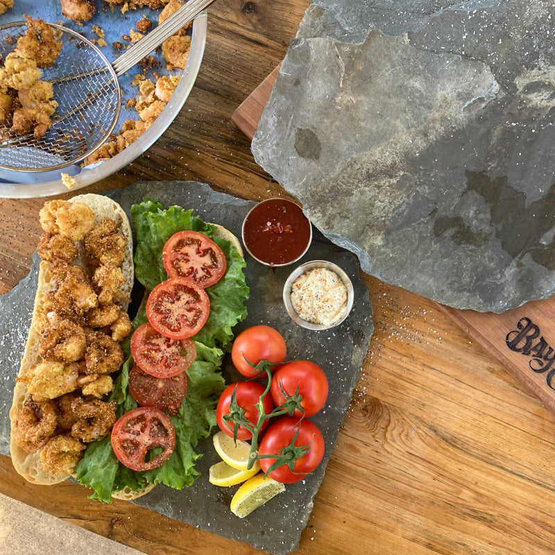 Open face shrimp poboy sandwich with fresh ingredients in an outdoor setting