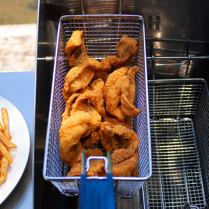fried fish in an outdoor fryer with a plate of french fries