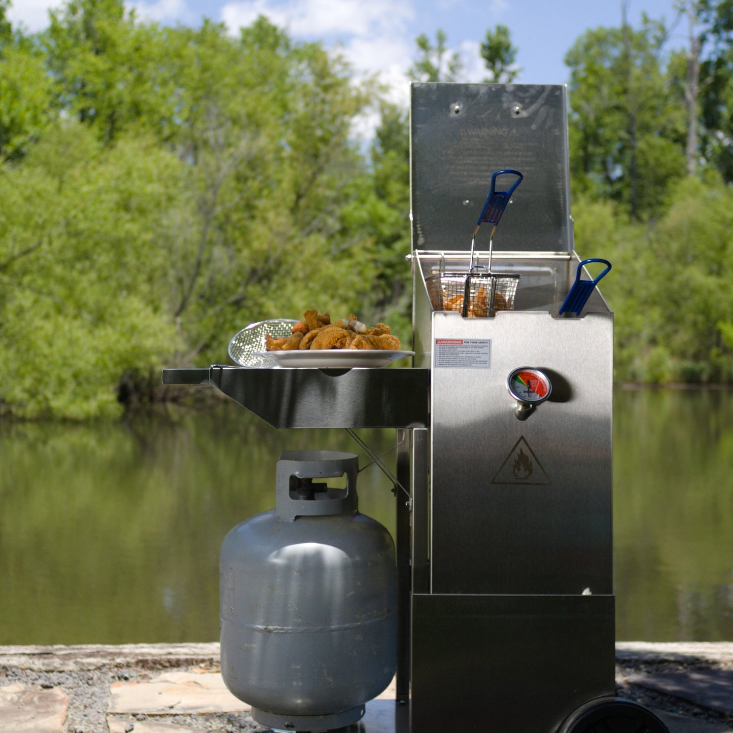 Portable gas grill with food on a dock by a body of water
