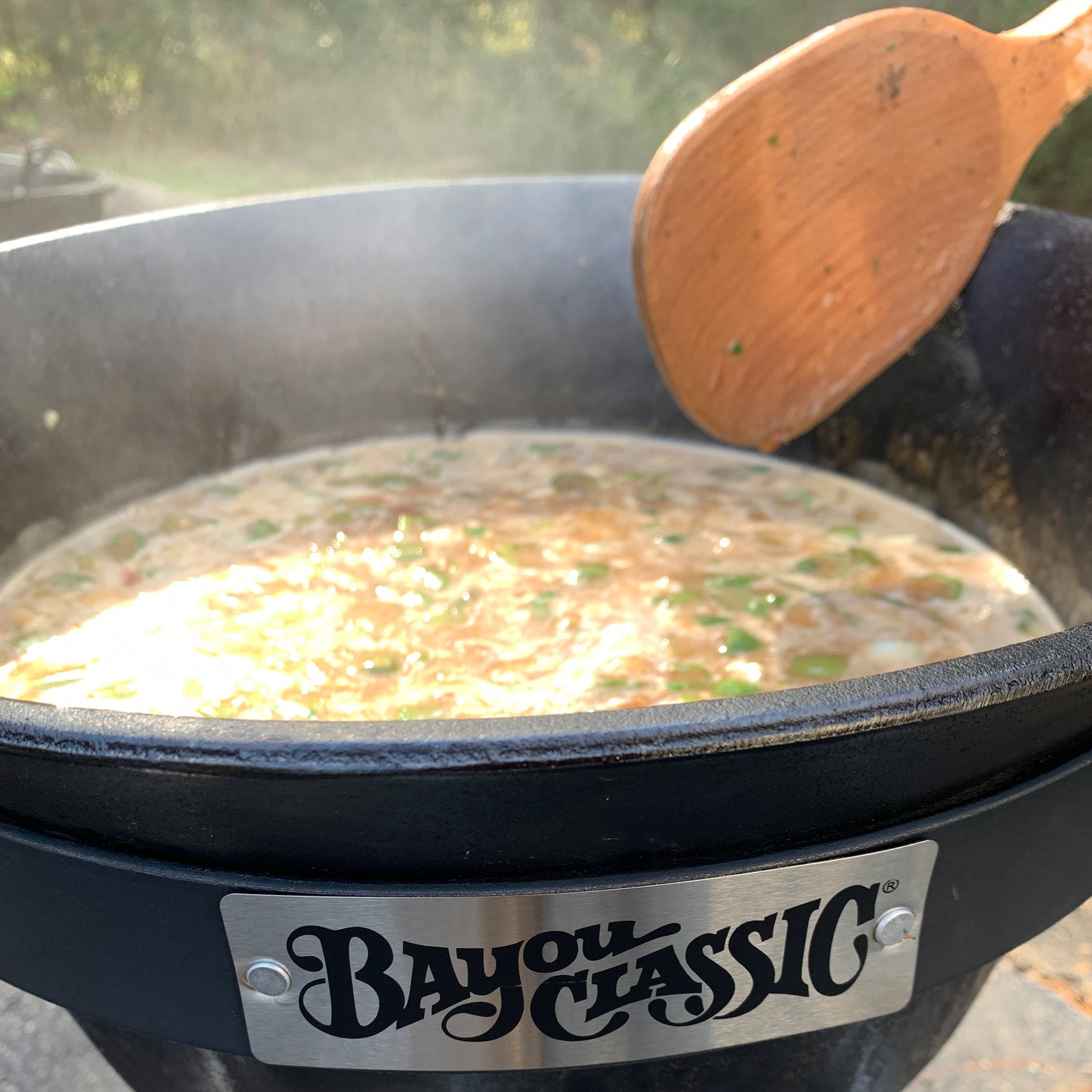 Stew being cooked in a cast iron pot with a wooden spoon.