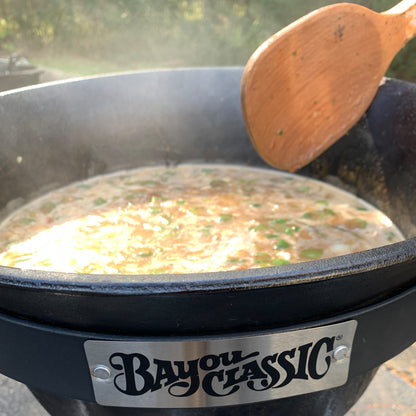 Stew being cooked in a cast iron pot with a wooden spoon.