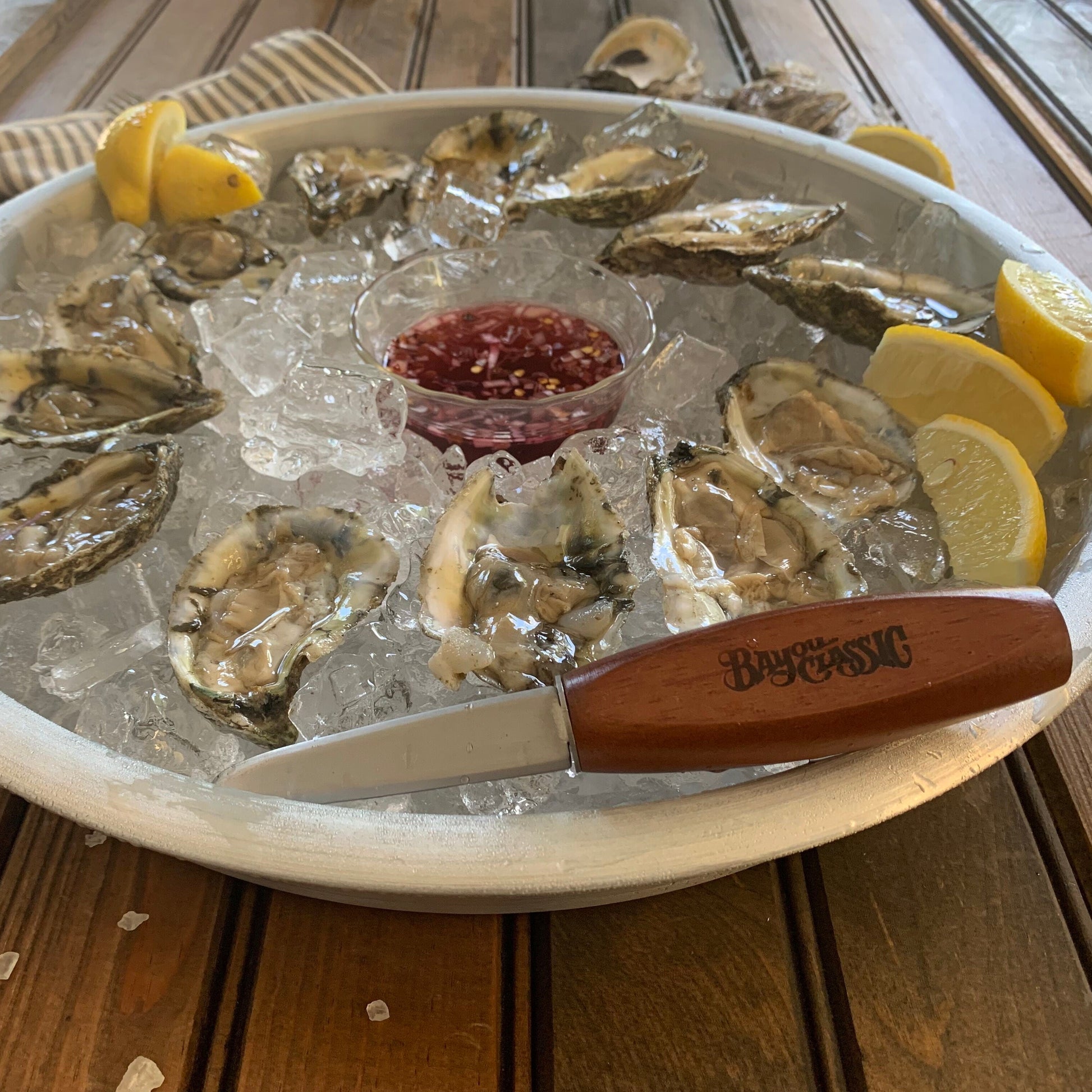 Bayou Classic oyster shucker knife resting on a silver tray of raw oysters over ice