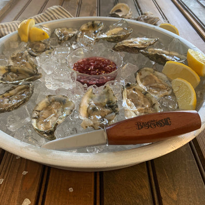 Bayou Classic oyster shucker knife resting on a silver tray of raw oysters over ice