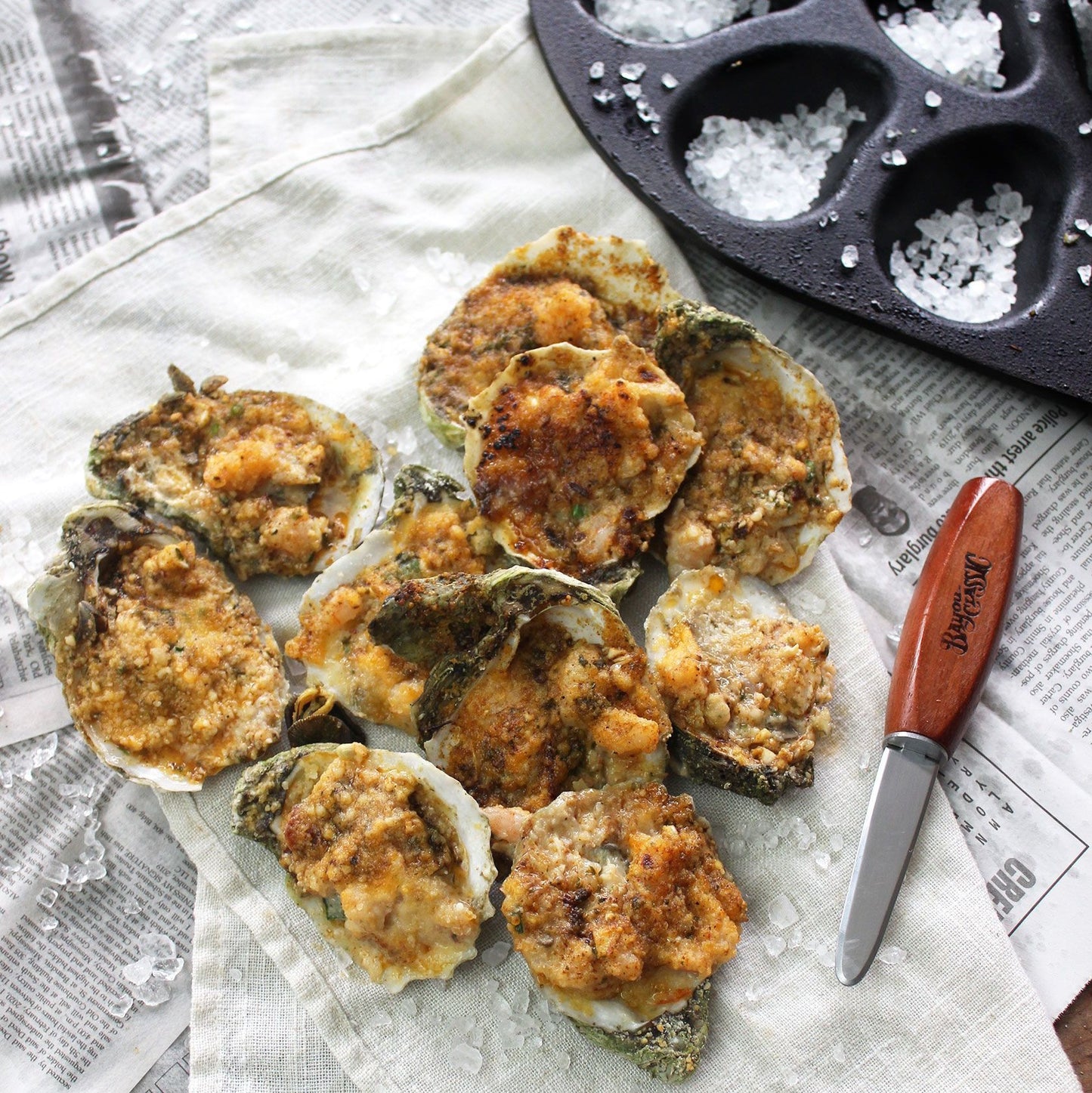 Chargrilled oysters arranged to make a heart shape with an oyster shucker knife