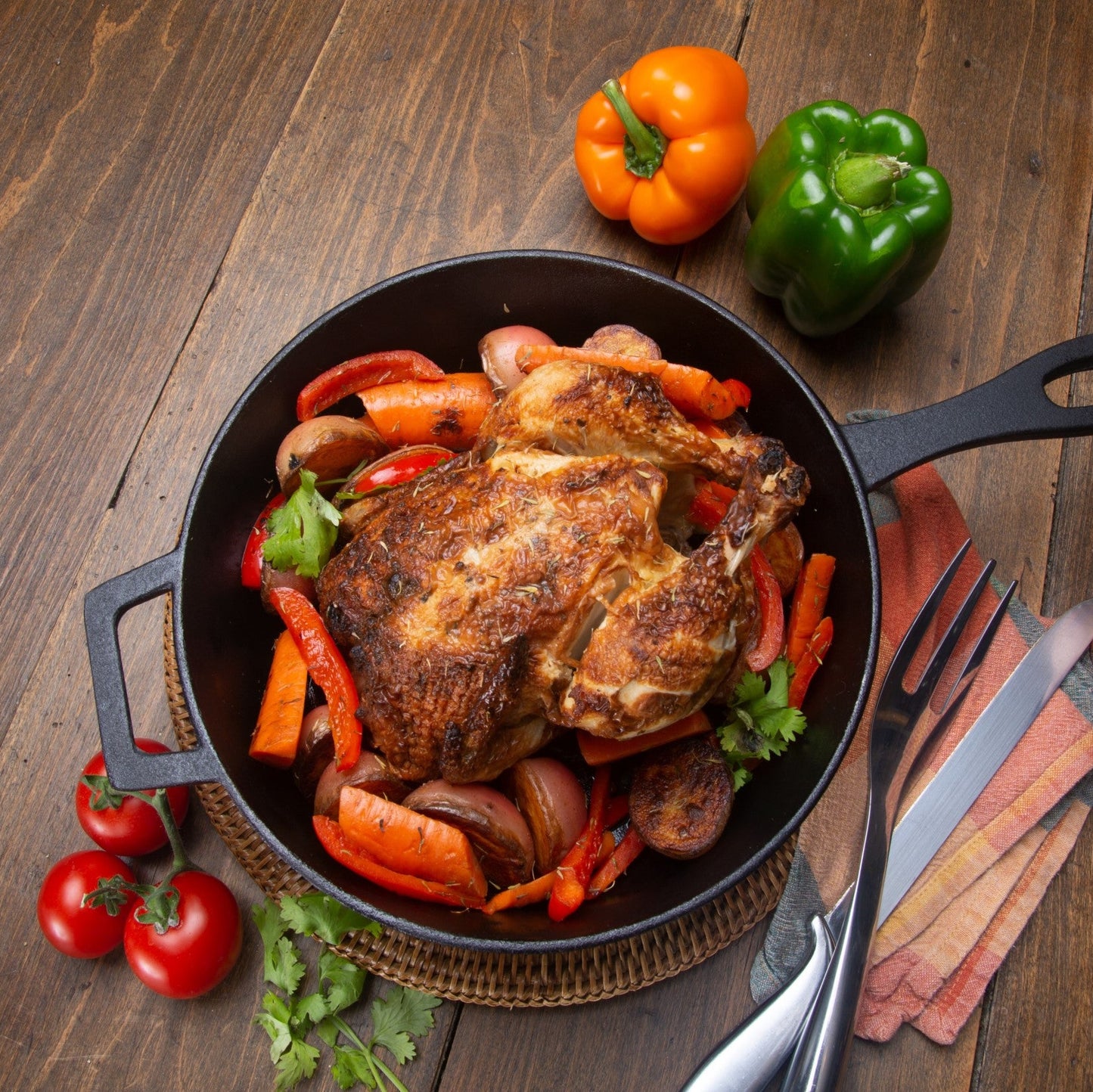 Roasted chicken with vegetables in a cast iron skillet on a wood table