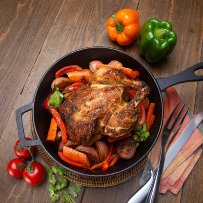 Roasted chicken with vegetables in a cast iron skillet on a wood table