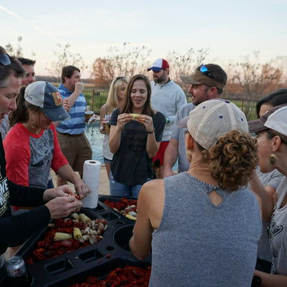 People outside around the seafood table eating crawfish